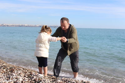 Father holding hands of daughter at beach