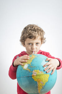 Portrait of boy holding camera over white background