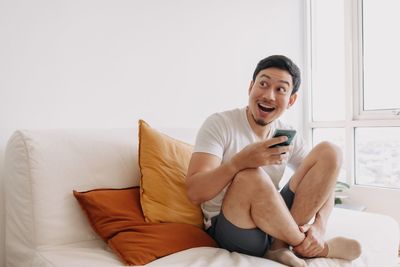 Young woman using laptop while sitting on bed at home