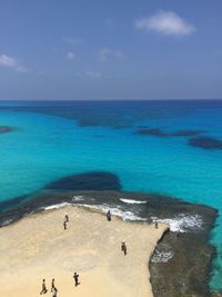 High angle view of people standing at beach against sky