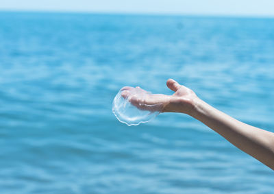 Close-up of hand holding sea against sky