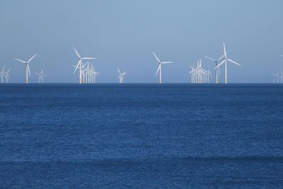 Wind turbines on sea against clear sky