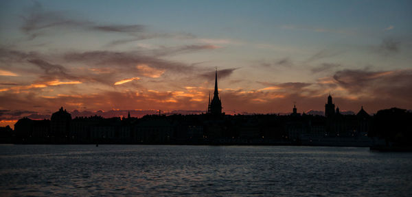 View of buildings at waterfront against cloudy sky