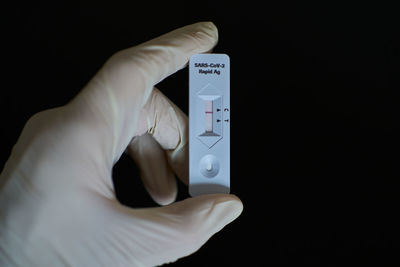 Close-up of hand holding mobile phone against black background