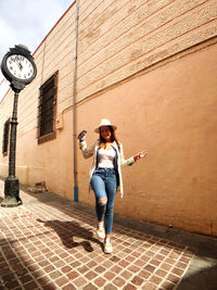 Full length of young woman standing against wall