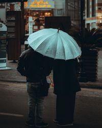 Rear view of people walking on wet street in rainy season