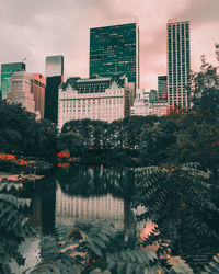 Reflection of buildings and trees in lake against sky