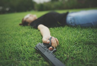 Woman lying on grass holding gun