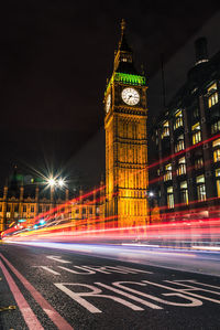 Light trails on road amidst buildings at night