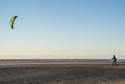 Woman kiteboarding at beach against clear sky