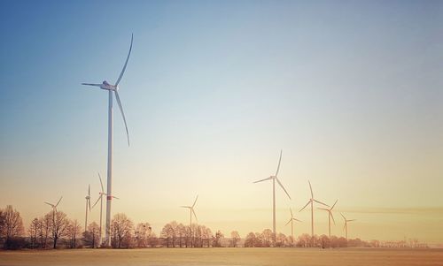 Wind turbines on field against clear sky