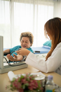 Woman using phone while sitting on table