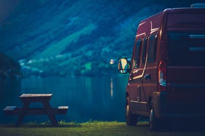 Vehicle and picnic table by lake during dusk