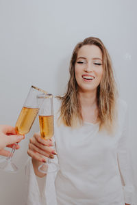 Smiling young woman holding drink against white background