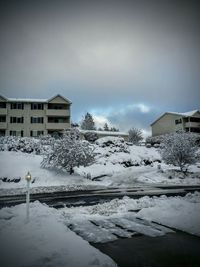 Snow covered houses against cloudy sky