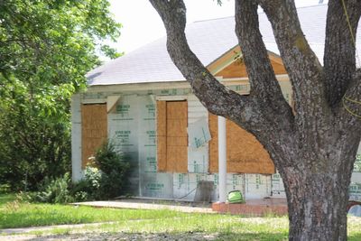 Built structure by trees on field against house