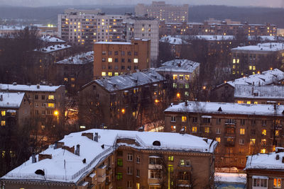 Snow covered buildings in city at dusk