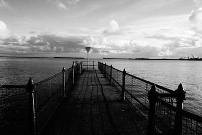 Pier leading to calm sea against sky