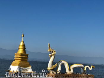 Statue of temple against clear blue sky