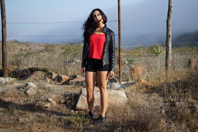 Full length of young woman standing on field in ensenada, mexico after tracking alone