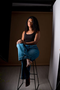 Portrait of young woman standing against wall