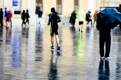 Rear view of people walking on wet street