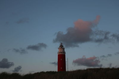 Lighthouse by dune against sky