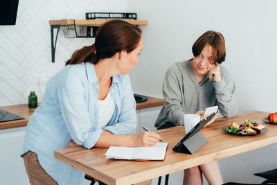 Mother and daughter eating food in kitchen