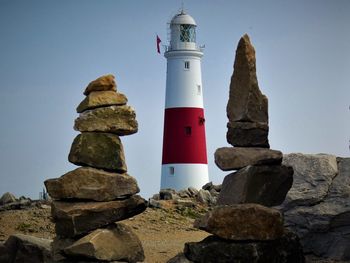 Low angle view of lighthouse against rocks and sky