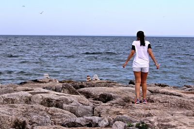 Rear view of woman standing on beach against clear sky