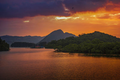 Scenic view of river by mountains against orange sky