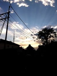 Low angle view of silhouette electricity pylon against sky