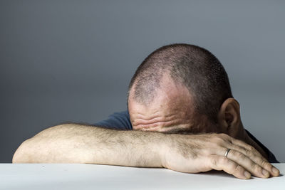 Portrait of man resting against gray background