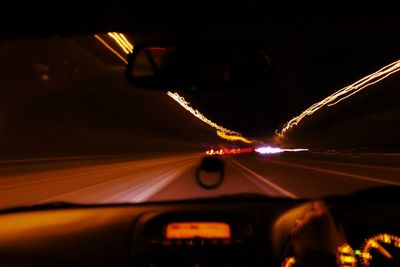 Light trails on road seen through car windshield at night