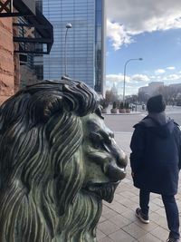 Rear view of statue against sky in city