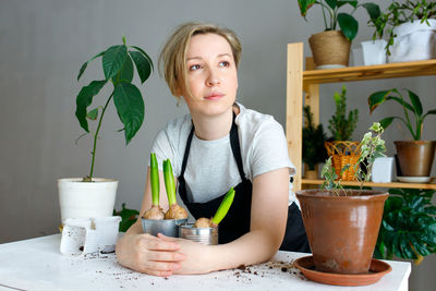 Portrait of young woman sitting on table at home