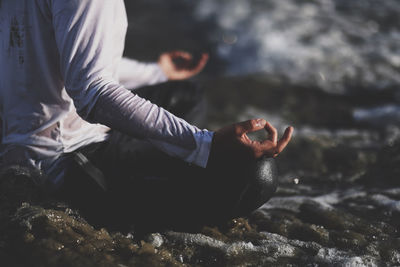 Low section of man meditating at beach