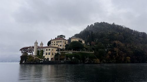 Buildings by lake against sky