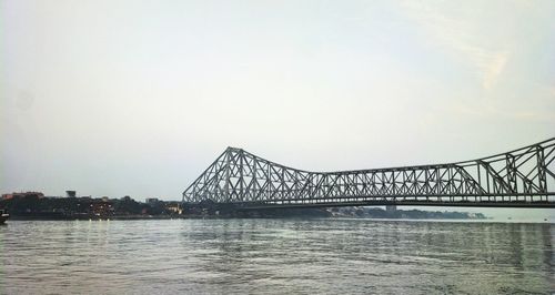 Bridge over river in city against sky