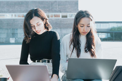 Female freelancers working on laptops during sunny day