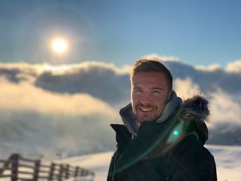 Portrait of man standing on snowcapped mountain against sky 