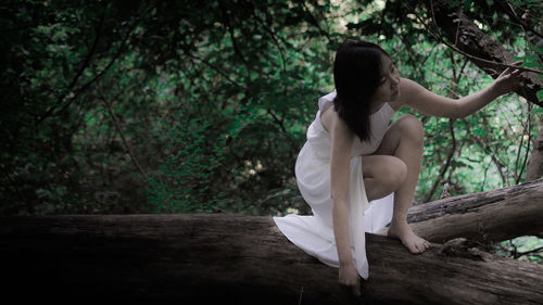 Side view of woman sitting in forest