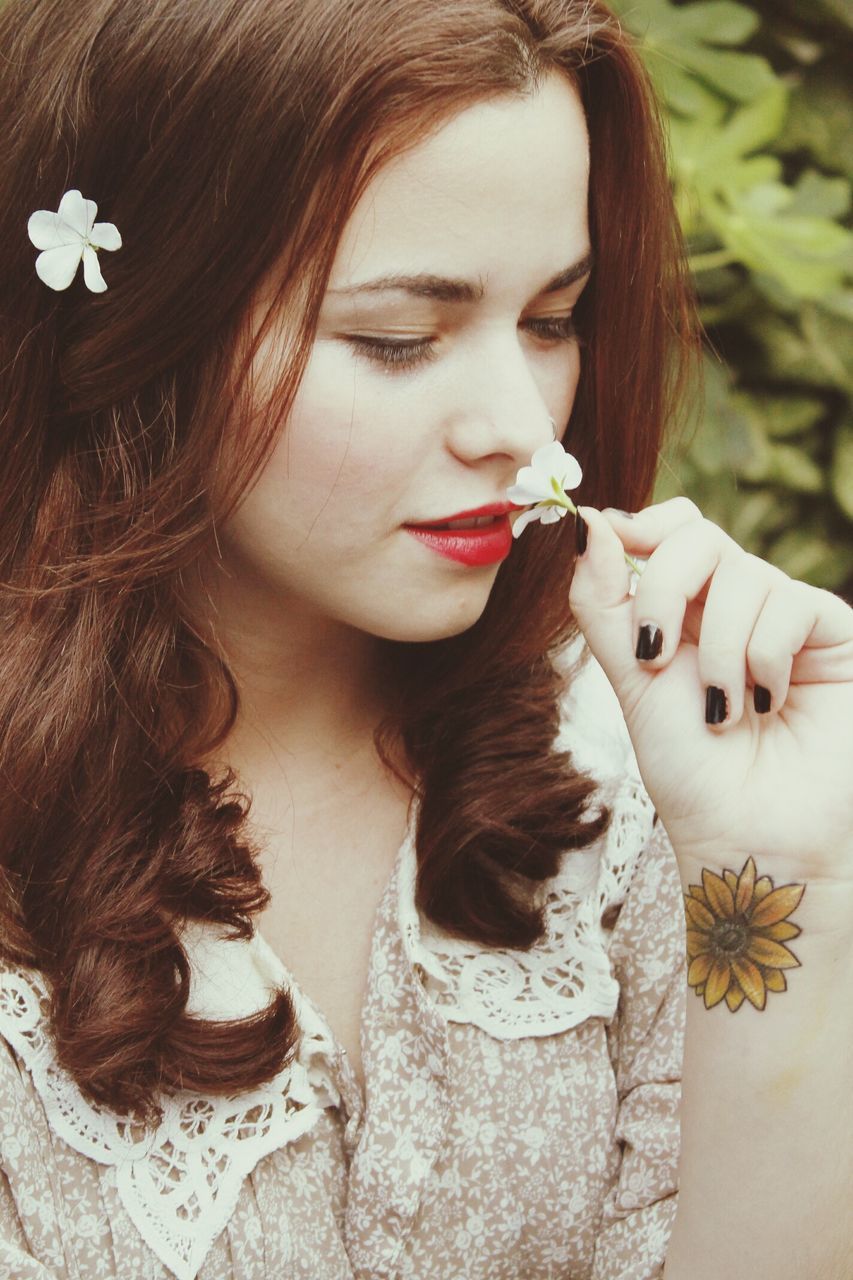 young women, long hair, young adult, lifestyles, person, leisure activity, portrait, looking at camera, flower, front view, beauty, close-up, femininity, headshot, holding, brown hair