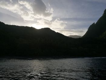 Scenic view of lake by silhouette mountain against sky