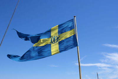 Low angle view of flag against blue sky