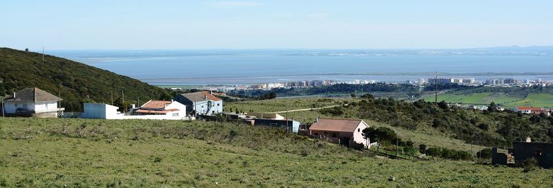 Scenic view of field by buildings against sky