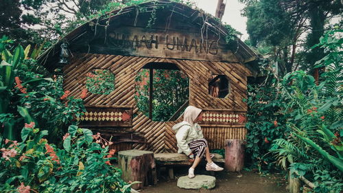 Girl sitting by plants outside house