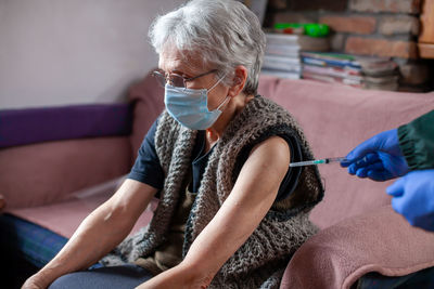 Cropped hand of doctor vaccinating senior woman