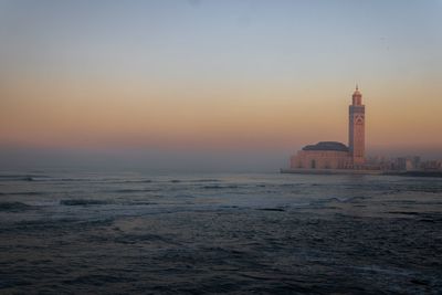 View of sea and hassan 2 mosque against sky during sunset 