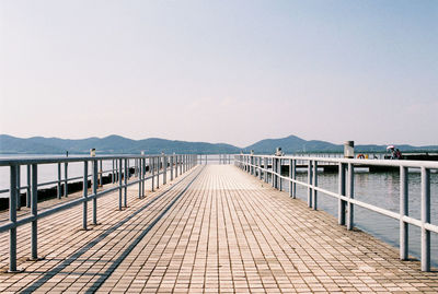 Pier over lake against clear sky